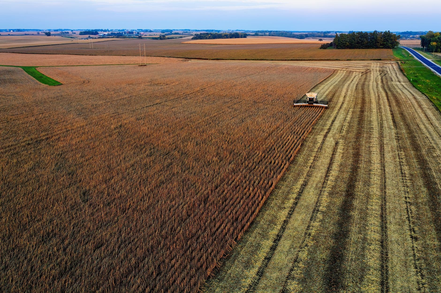 Aerial view of a combine harvester working in expansive cropland in Minnesota, USA.